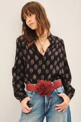 Camisa negra con estampado floral blanco, de corte regular, con volados en el cuello y cierre frontal con botones.