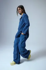 Pantalón jean azul denim de tiro medio, corte oversize y bolsillos cargo laterales y delanteros.