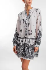 Vestido de corte fluido con estampado en blanco y negro, mangas largas y detalle de bordado.