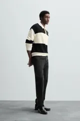 Sweater tipo polo de punto con rayas horizontales anchas en color negro y crudo, con cuello clásico y cierre de dos botones.