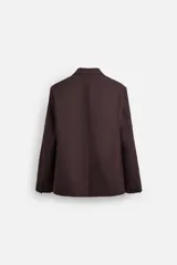 Blazer color borgoña de corte regular, con cuello de solapas de muesca, manga larga con puños abotonados, bolsillos de doble vivo en la cadera, bolsillo interior, abertura en el centro de la espalda y cierre frontal con botonadura.