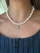 Gargantilla de cuentas blancas con dije de estrella de mar dorada.