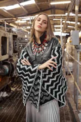 Poncho de cuero ovino negro con corte de chaqueta y mangas tejidas en lana con diseño geométrico en blanco y negro.