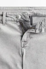 Jean acampanado de tiro bajo, color gris claro, confeccionado en denim levemente elástico.