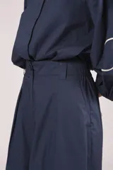 Pantalón palazzo azul marino con bordado de flores blancas en la parte inferior de ambas piernas. El pantalón tiene talle alto y pinzas en la cintura.