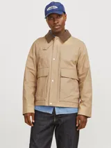 Chaqueta estilo workwear color arena con cuello marrón de pana y acabado satinado. Tiene cierre frontal con botones a presión, mangas largas, bolsillos frontales tipo parche y puños abotonados.