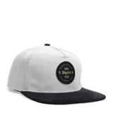 Gorro estilo snapback de dos tonos, corona gris claro y visera plana negra. Presenta un parche circular bordado en el frente con diseño gráfico en verde neón y negro.