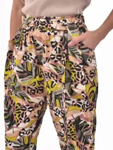 Pantalón babucha de tela estampada con hojas en tonos rosa, naranja y azul, con cintura elastizada y lazo para ajustar.