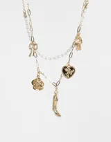 Collar corto doble, uno con cadena dorada con dijes de bota cowboy, rosa, corazón y herradura, y otro con perlas.