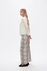Pantalón jean ancho con estampado de piel de serpiente en tonos beige y gris.