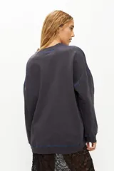 Buzo gris de corte holgado con bordado azul en el frente y costuras a contratono.