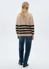 Sweater beige con cuello alto y rayas horizontales negras con hilo dorado.