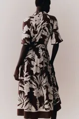 Vestido midi camisero color marrón con estampado floral blanco, cuello camisero, botonadura frontal y mangas cortas. Incluye cinturón extraíble para atar.