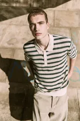 Polo de punto color crema con rayas horizontales verde oscuro, cuello clásico y cierre de botones.