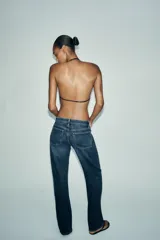 Top negro con escote drapeado y tiras finas ajustables en cuello y espalda. Detalle de aplicación de abalorios.