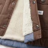 Campera marrón con cuello de pana, cierre frontal con botones a presión, dos bolsillos frontales con solapa y etiqueta con logo de la marca en el lateral.