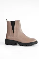 Bota corta color beige de cuero, con elásticos laterales negros, suela track y tirador trasero.