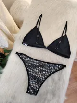Conjunto de bikini negro con aplicaciones plateadas. El corpiño es de corte triangular con tirantes finos regulables y la bombacha es tipo colaless con laterales regulables.