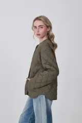 Campera acolchada negra, con diseño capitoné en rombos, cuello redondo y cierre frontal con botones a presión. Posee bolsillos delanteros amplios.