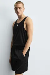 Bermuda negra de corte relajado, confeccionada en tejido satinado de viscosa. Presenta cintura elástica ajustable con cordón interior, bolsillos frontales y un bolsillo trasero de plastrón.