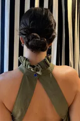 Vestido largo verde oliva de tela simil agamuzada, con escote halter, espalda baja y volados en cuello y cadera.