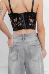 Corset crop negro de encaje con lentejuelas bordadas, estructura interna, copas armadas, breteles regulables y cierre trasero.