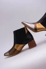 Botinetas de cuero con diseño patchwork en negro, dorado, plateado y marrón. Tienen elásticos laterales, taco cuadrado de madera y puntera fina.