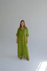 Vestido camisero largo color verde oliva, de lino italiano, con cuello camisero, mangas largas con puños abotonados y cierre frontal con botones. Tiene corte recto y fluido.