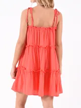 Vestido corto color naranja oscuro, con breteles finos y volados en el escote y en los cortes de la falda.