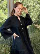 Vestido corto negro de lino, con escote en V, botones frontales y mangas largas acampanadas con volados.