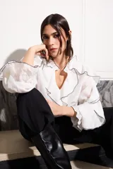 Camisa blanca con volados con terminación de hilo negro en cuello, mangas y frente.