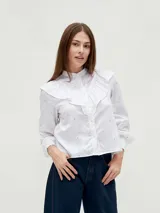 Camisa blanca con cuello mao, volantes frontales y mangas largas con puños elásticos. Estampado floral pequeño en tonos rosados.