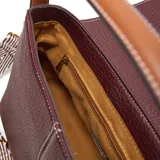 Bandolera de PU color bordó con textura granulada y costuras blancas visibles. Presenta solapa frontal con logo metálico XL y herrajes dorados. Incluye correa larga regulable y desmontable, y asa superior de cuero marrón.