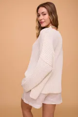 Buzo color crema tejido en algodón, de silueta holgada, mangas anchas y cuello bote.