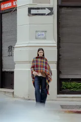 Ruana tejida multicolor con diseño geométrico y flecos.