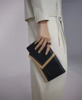Sobre cartera Adolfo Dominguez de cuero negro con solapa asimétrica y detalle de serraje color beige. Cierre con broches.
