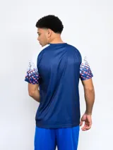 Remera deportiva azul con el escudo del Club Nacional de Football en el pecho y diseño de cuadros rojos y blancos en las mangas.