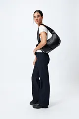 Pantalón de jean azul oscuro, de corte flare con cinturón incorporado en la misma tela y silueta ajustada en cadera que se ensancha hacia el ruedo.