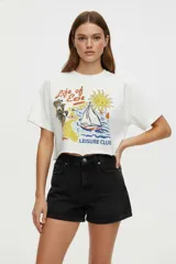 Remera blanca de algodón con estampado de texto y gráficos alusivos a la playa. Corte crop y cuello redondo.