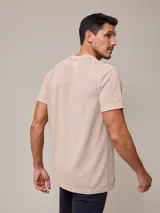 Remera beige de piqué con cuello redondo y logo bordado en blanco.