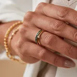 Anillo solitario de oro amarillo 18k con un brillante engarzado en 4 puntas y un anillo con esmeraldas engarzadas.