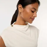 Top blanco sin mangas con cuello alto y botón decorativo en el hombro.