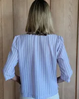 Camisa color beige claro con cuello con volados y mangas 3/4 abullonadas.