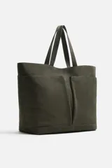 Bolso tipo shopper color verde musgo, confeccionado en cuero con acabado serraje. Tiene compartimento principal con cierre magnético, cuatro bolsillos exteriores y un bolsillo interior con cierre.
