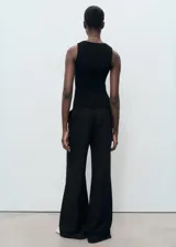 Musculosa negra de tejido de punto fino, con cuello redondo y tirantes anchos.