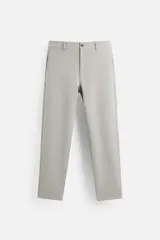 Pantalón gris claro de corte slim fit, confeccionado en tejido elástico. Cuenta con bolsillos frontales y traseros de vivo con botón. Cierre frontal con cremallera y botón.