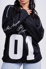 Remerón negro de corte holgado con estampado frontal del número 01 en blanco y la frase "Los Angeles" en las mangas.