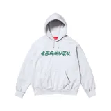 Canguro gris con capucha y bolsillo delantero, con logo Supreme en tipografía gótica verde.