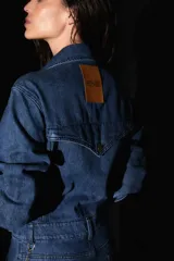 Mono largo de denim azul, con bolsillos delanteros y traseros, badana de PU en la espalda y avíos metálicos.