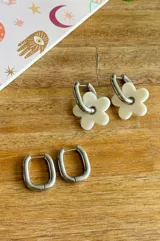 Aros de acero quirúrgico dorados con dije de flor acrílica blanca.